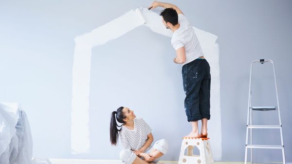 Couple painting house shape on wall in new apartment