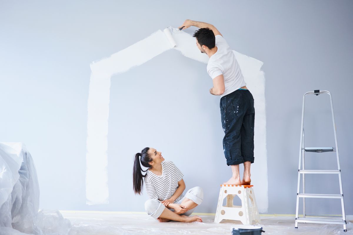 Couple painting house shape on wall in new apartment