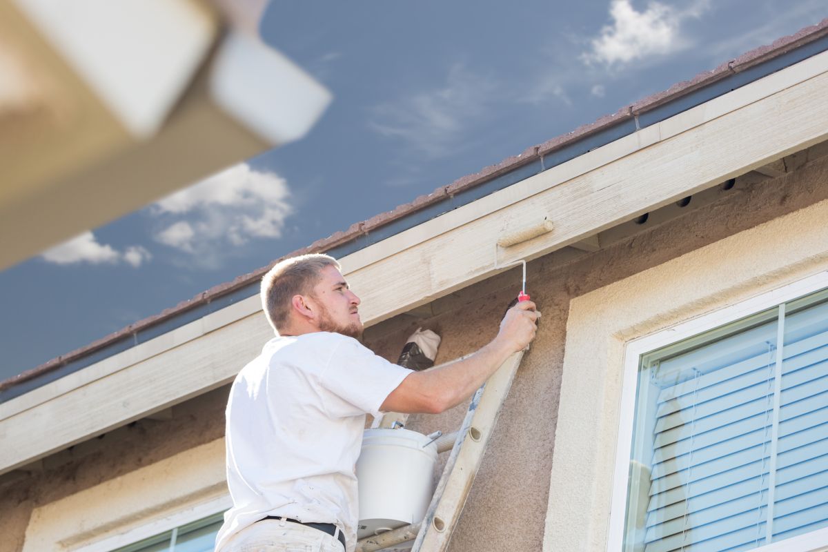 Professional Painter Using A Small Roller to Paint House Fascia.