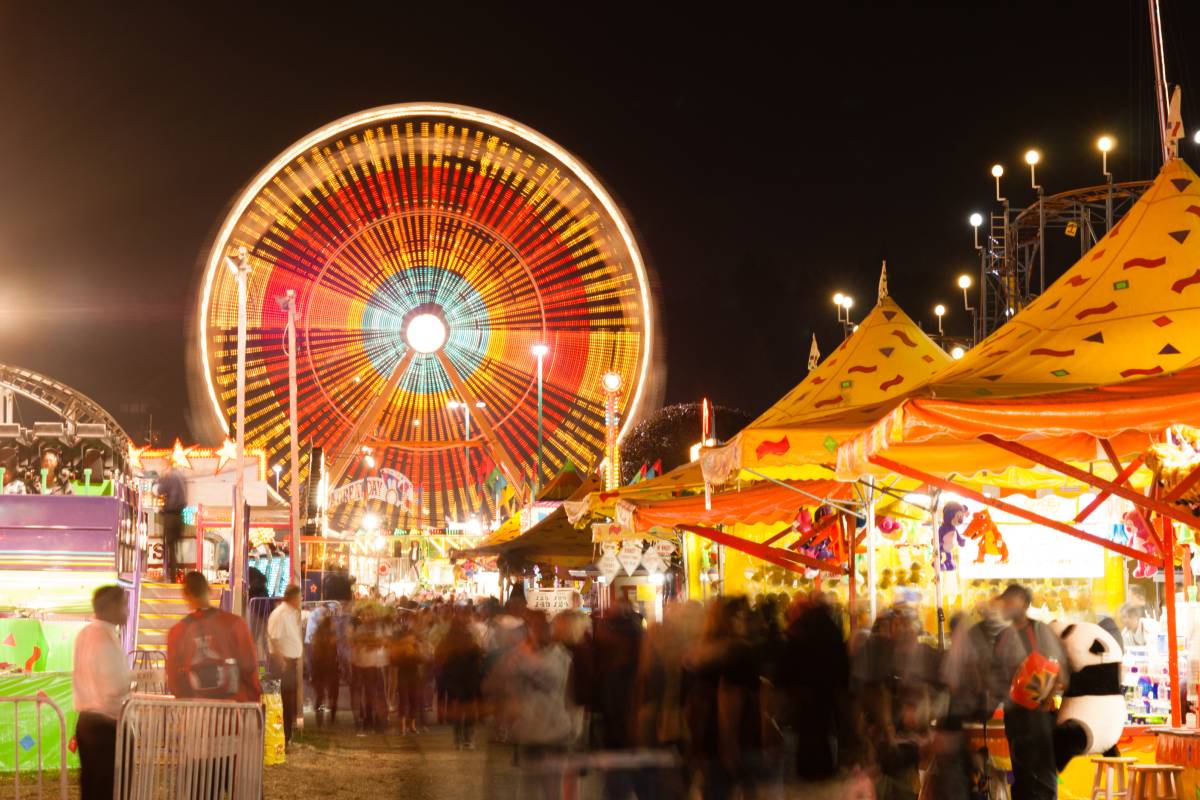The midway is all lit up at night with motion occuring in this long exposure at the state fair