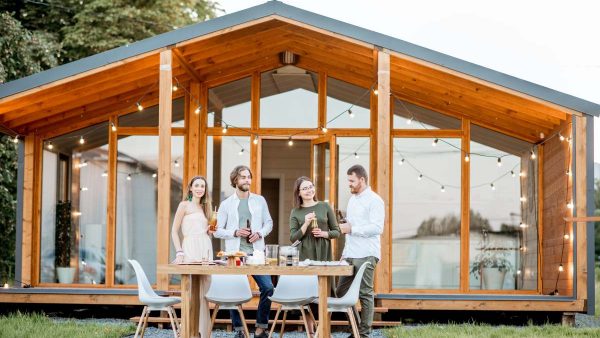 Four friends enjoying evening time together drinking beer on the backyard of the modern country house