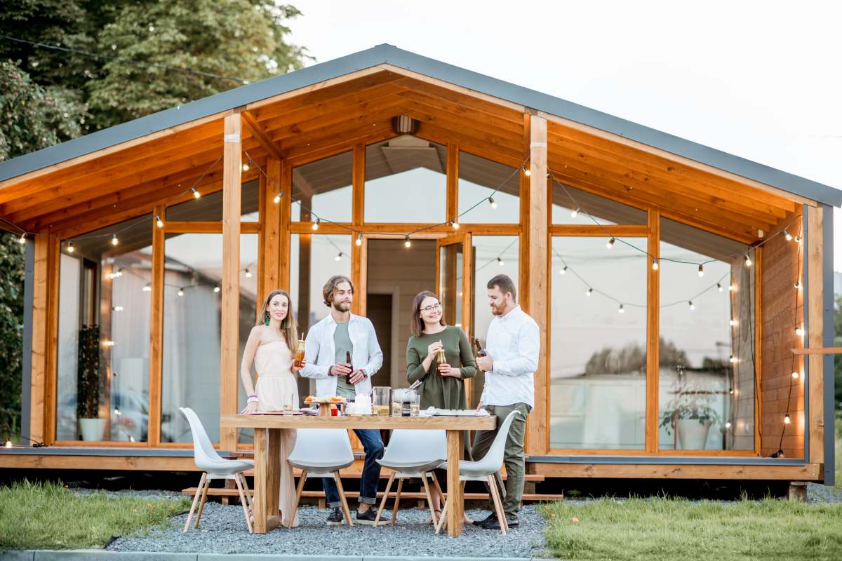 Four friends enjoying evening time together drinking beer on the backyard of the modern country house